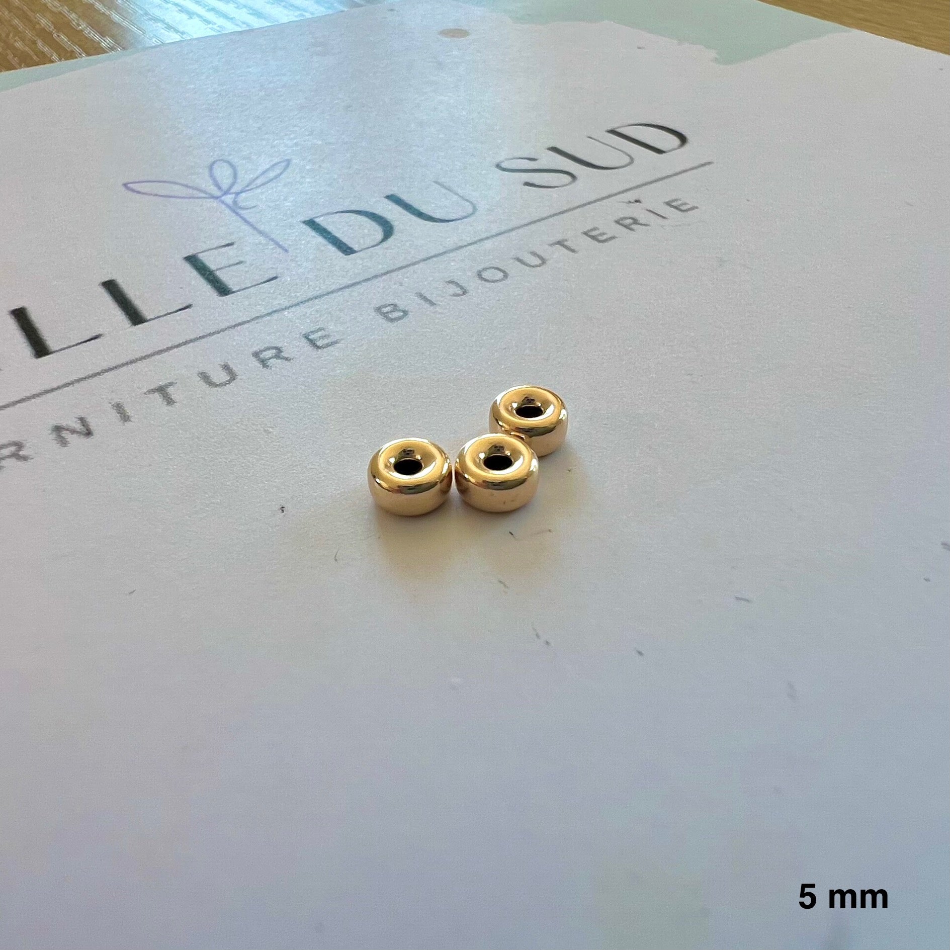 Perle intercalaire de forme rondelle en or jaune 9 carats (375/1000), diamètre 5 mm avec deux trous.