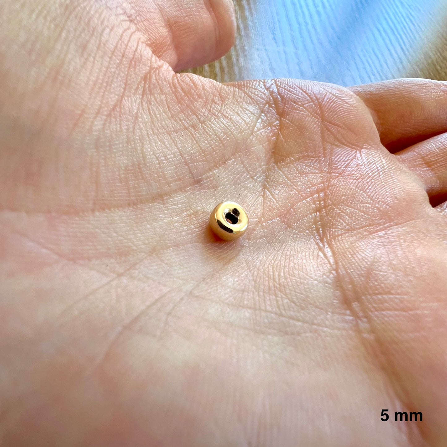 Aperçu de la taille réelle d'une perle intercalaire rondelle de 5 mm dans la paume d'une main