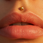Piercing labret lèvre en or jaune 18 carats avec boule de 3,4mm porté au-dessus de la lèvre au soleil.