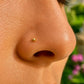 Gros plan sur la narine d'une personne portant un piercing nez boule en or jaune 18 carats, un bijou de nez discret et élégant de l'atelier La Fille du Sud.
