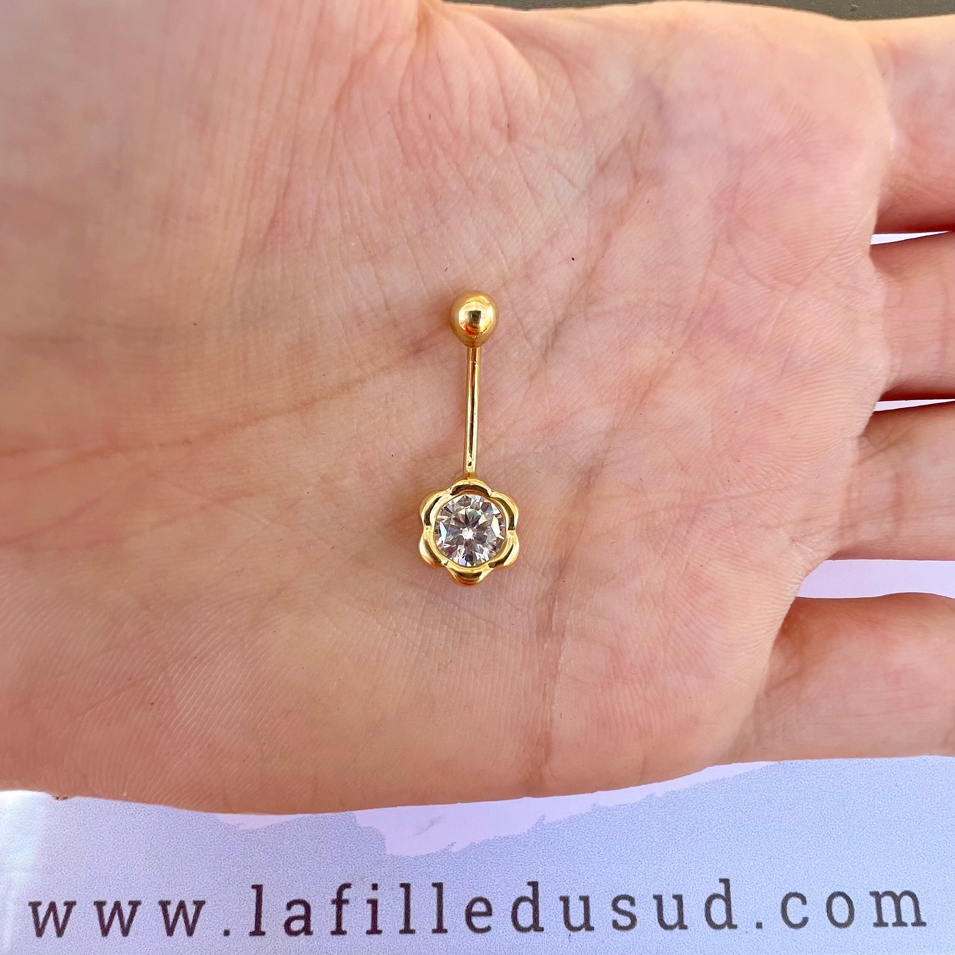 Taille réelle du piercing de nombril fleur en or jaune 18 carats dans la paume d'une main.