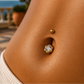 Gros plan sur le nombril d'une femme portant un piercing en forme de fleur en or jaune 18 carats serti d'un oxyde de zirconium.