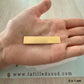 Aperçu de la taille réelle de la plaque d'or de 5x1 cm dans la paume de la main d'un créateur.