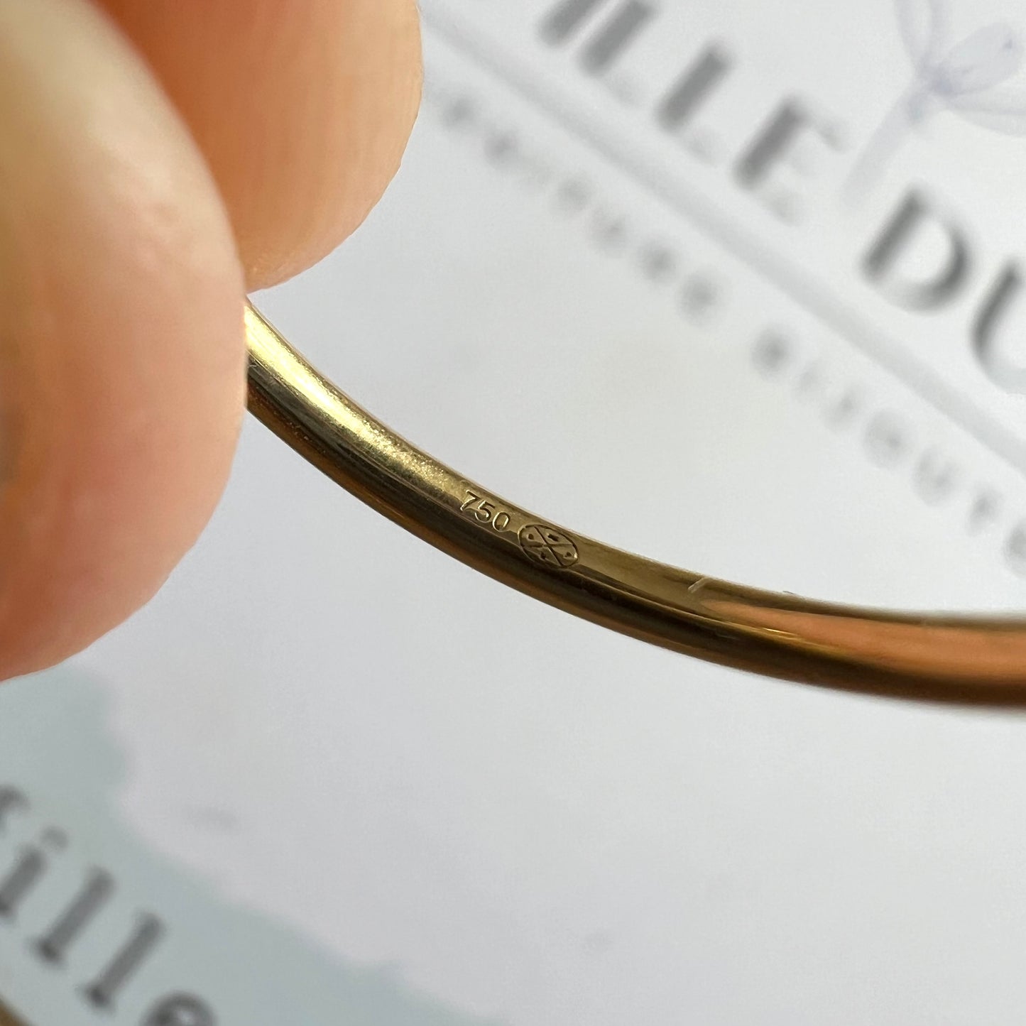 Zoom sur le poinçon d'état 750 garantissant l'authenticité de l'or 18 carats massif de la bague trèfle.