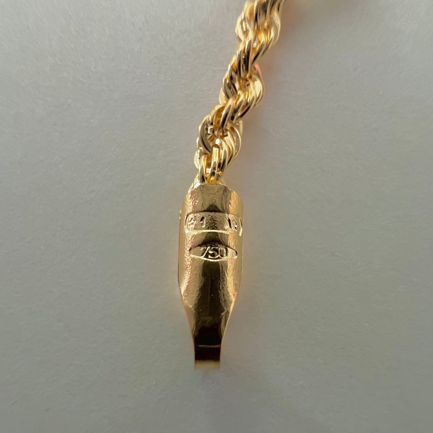 Gros plan sur le poinçon d'état 750 garantissant l'authenticité de l'or 18 carats massif du bracelet maille corde.