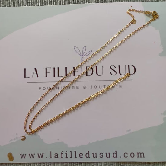Chaîne homme maille forçat miroir en or jaune 18 carats posée sur son support de marque La Fille du Sud
