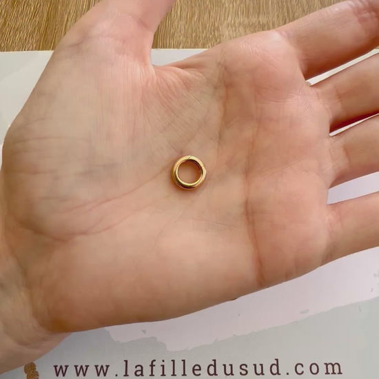 Démonstration du système de charnière invisible sur un fermoir rond en or rouge 18k.