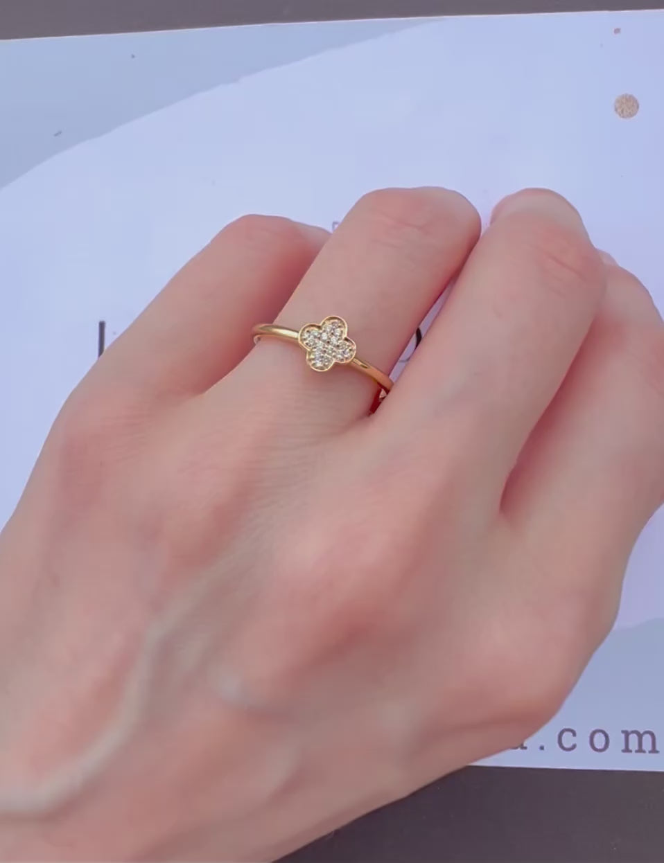 Démonstration de la bague trèfle en or et diamants portée à la main en mouvement sous la lumière.