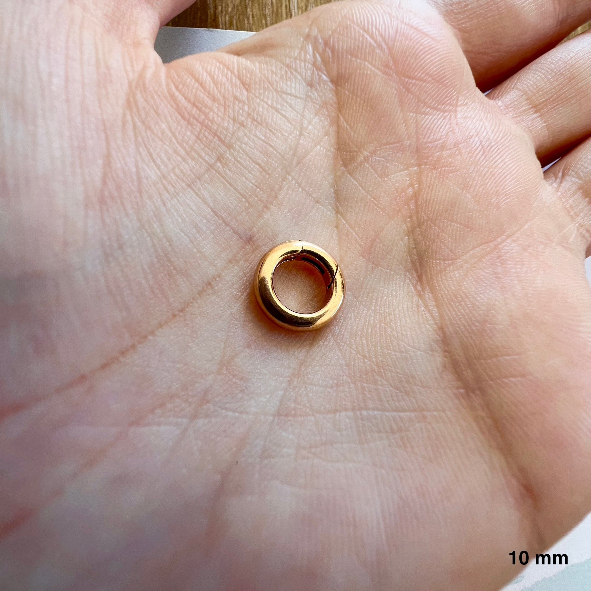 Éclat et proportion d'un petit fermoir rond en or rouge massif 18 carats pour création artisanale.