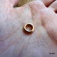 Éclat et proportion d'un petit fermoir rond en or rouge massif 18k pour création artisanale.