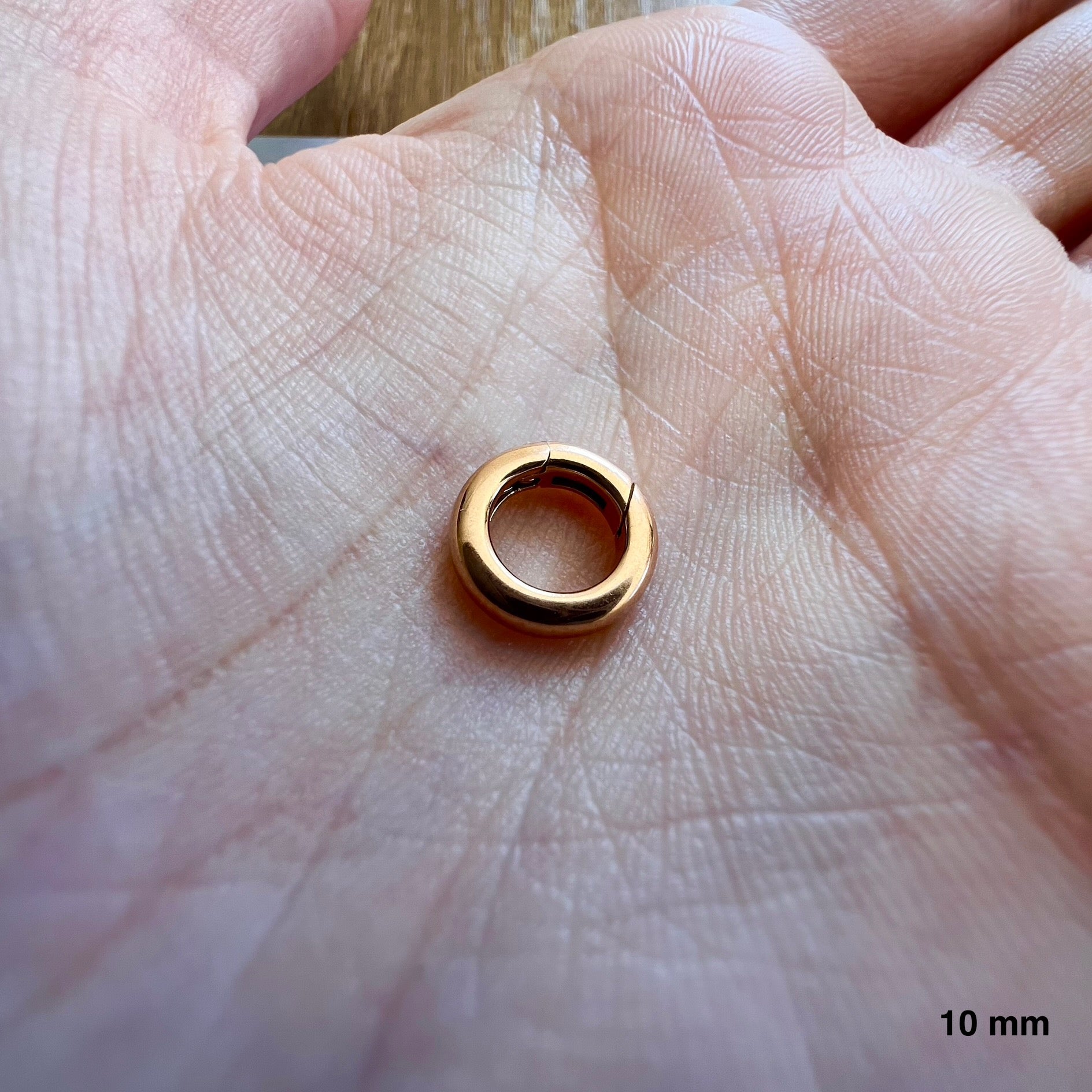 Éclat et proportion d'un petit fermoir rond en or rouge massif 18k pour création artisanale.