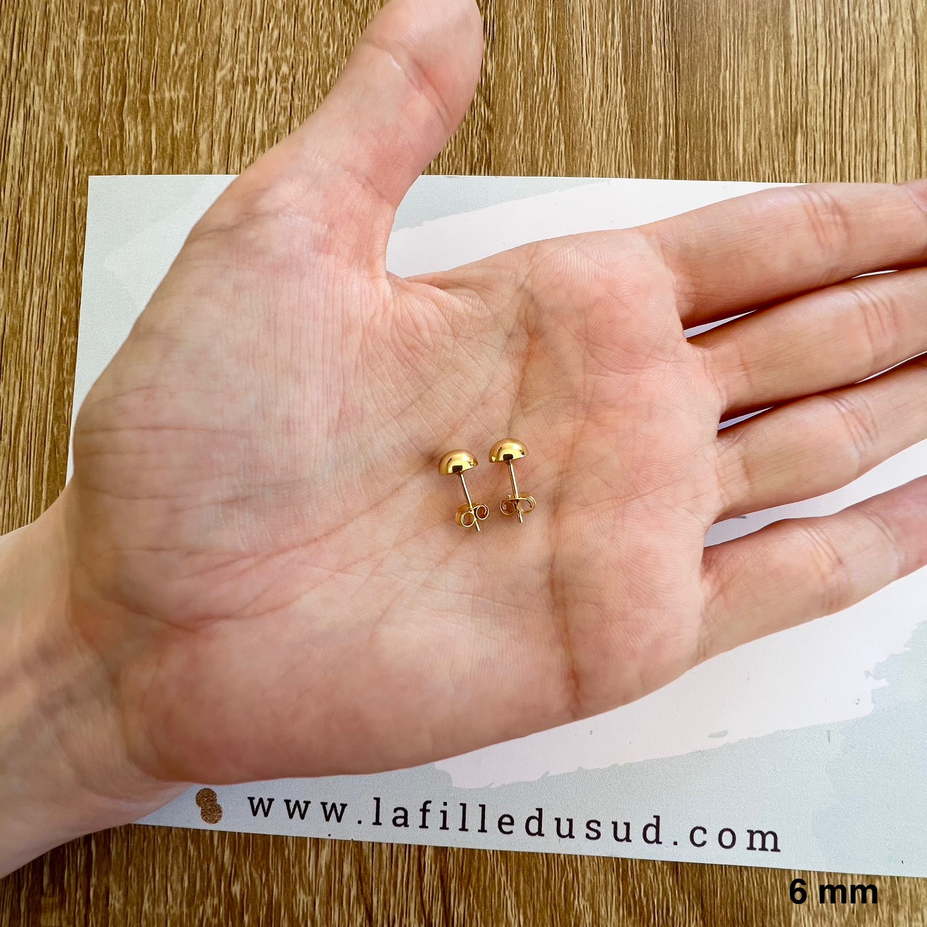 Aperçu de la taille réelle des puces d'oreilles demi-rond de 6 mm dans la paume d'une main