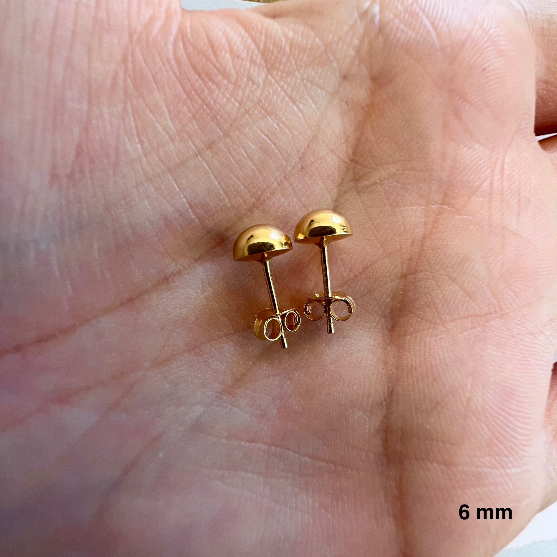 Aperçu de la taille réelle des puces d'oreilles demi-sphere de 6 mm dans la paume d'une main