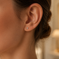 Oreille de femme portant une puce d'oreille en diamant solitaire et or jaune 18 carats, éclat naturel et élégance minimaliste.