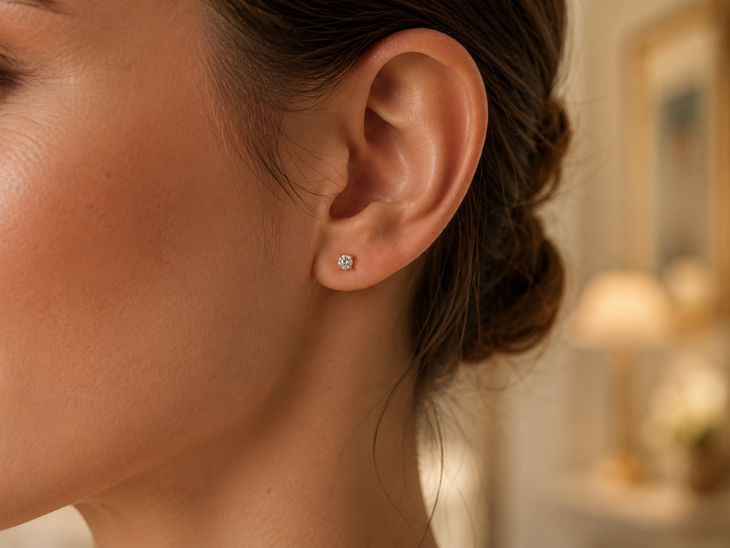 Oreille de femme portant une puce d'oreille en diamant solitaire et or jaune 18 carats, éclat naturel et élégance minimaliste.