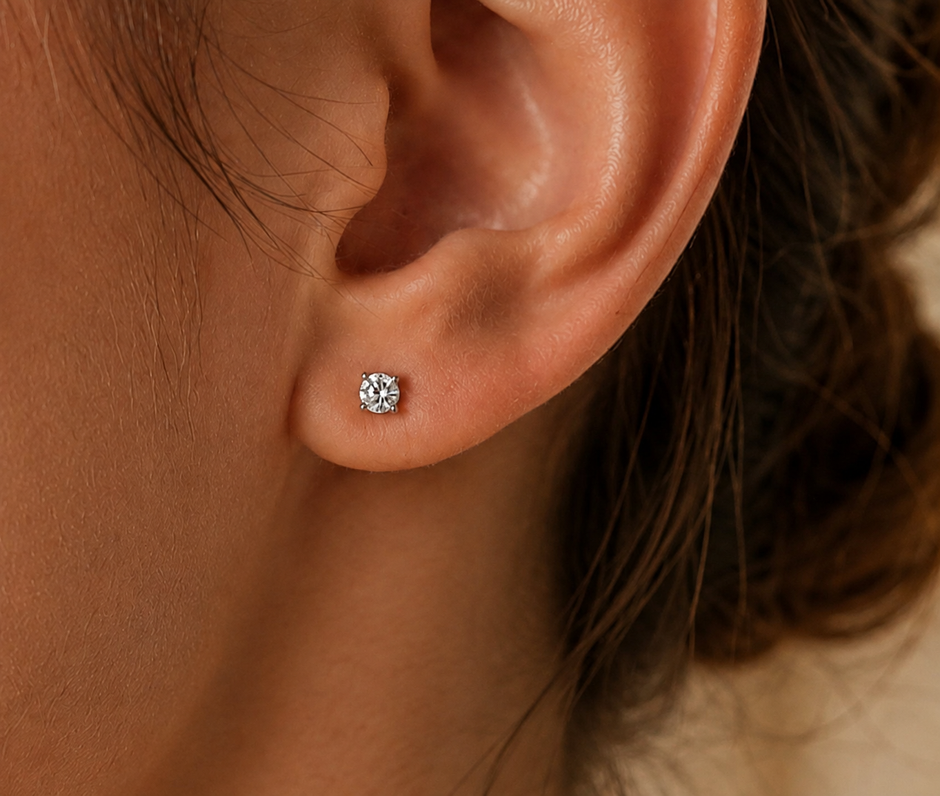 Femme portant une puce d'oreille en diamant solitaire et or blanc 18 carats, éclat naturel et élégance minimaliste.