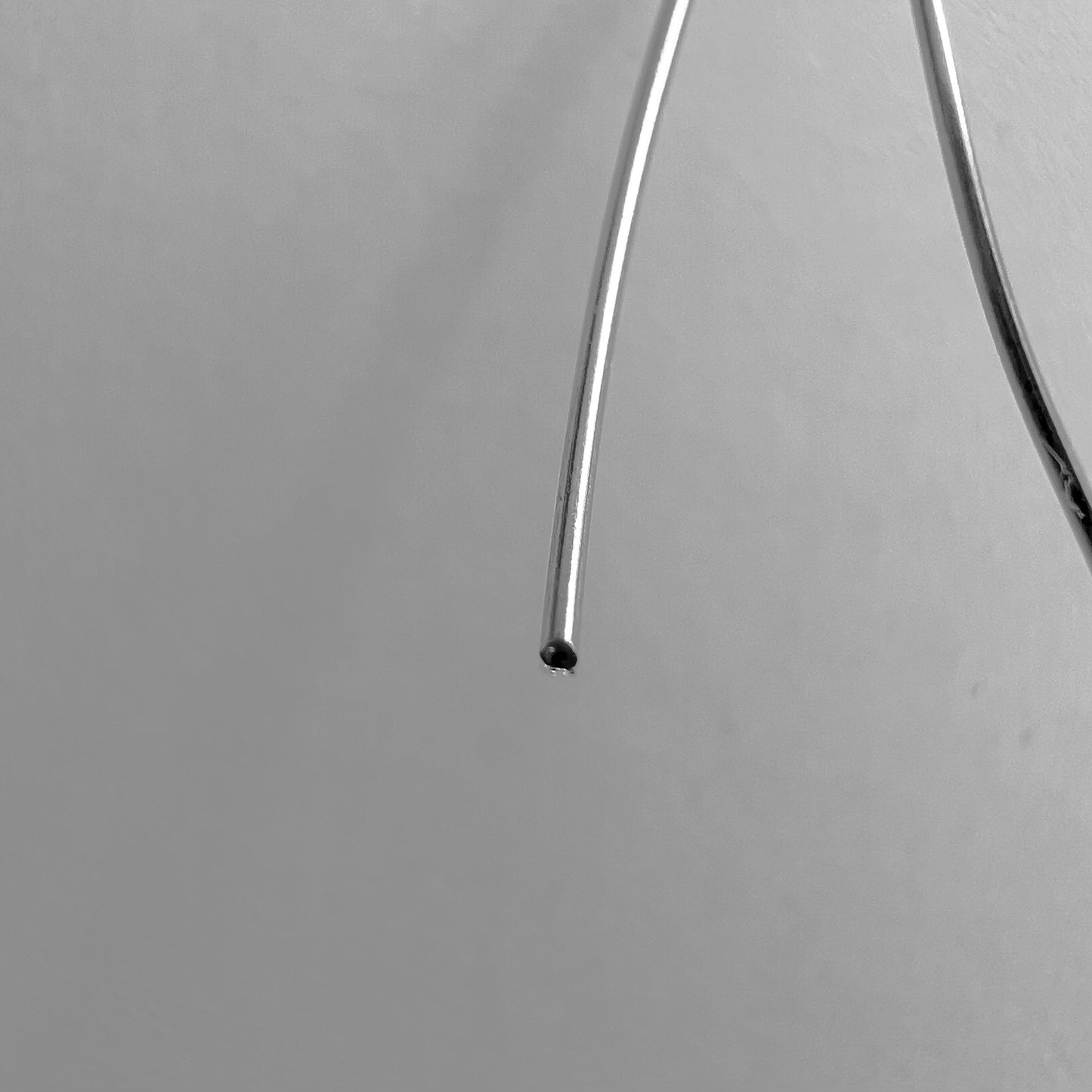 Macro sur la coupe nette d'un fil d'or 18k de 0,50mm montrant la section parfaitement ronde et pleine.