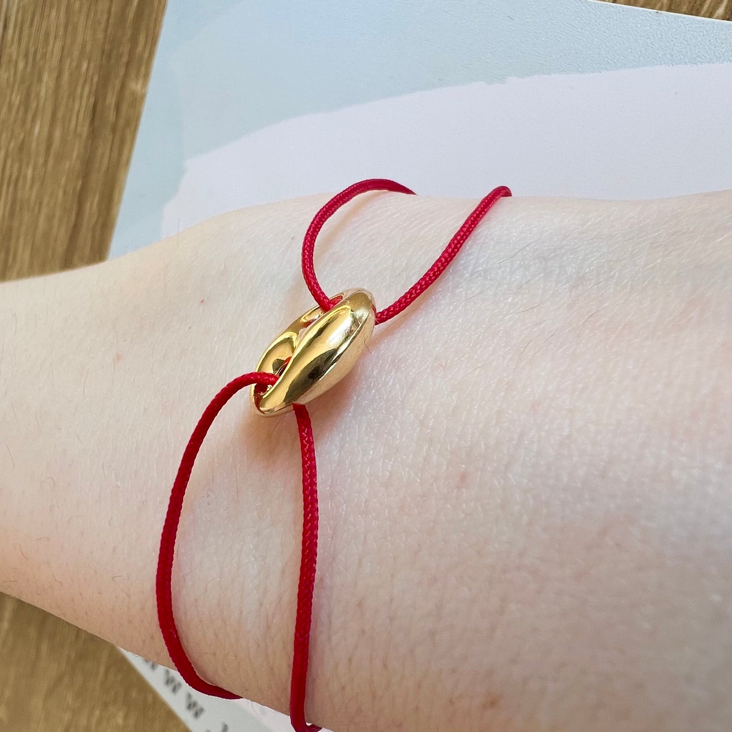 Bracelet cordon rouge porte-bonheur avec un graine de café en or 18 carats.